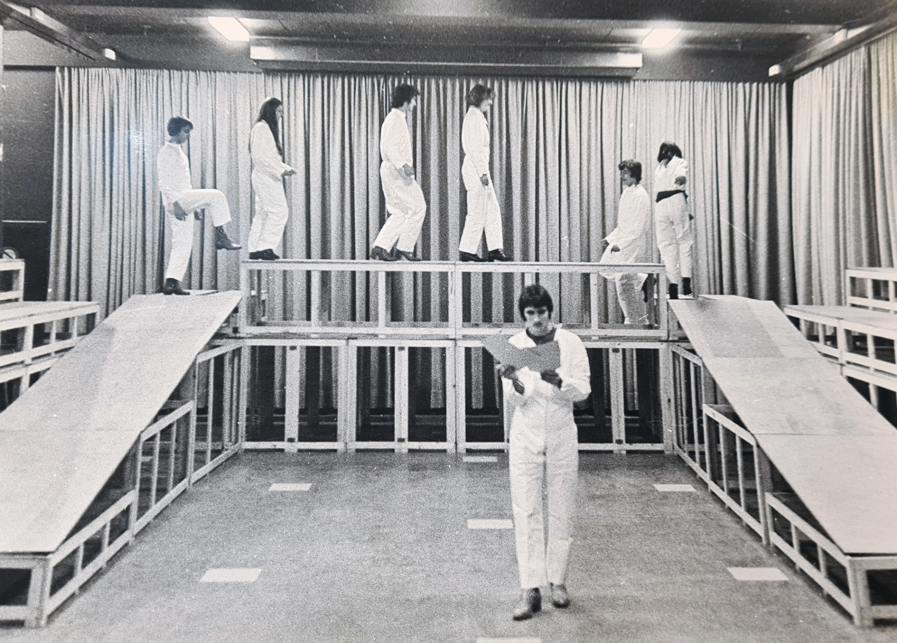 Performers in witte overalls op een meerlagige scène in Stuc